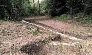 Here, the 1,900-year-old building before it was excavated. Trees and bushes grew over it.