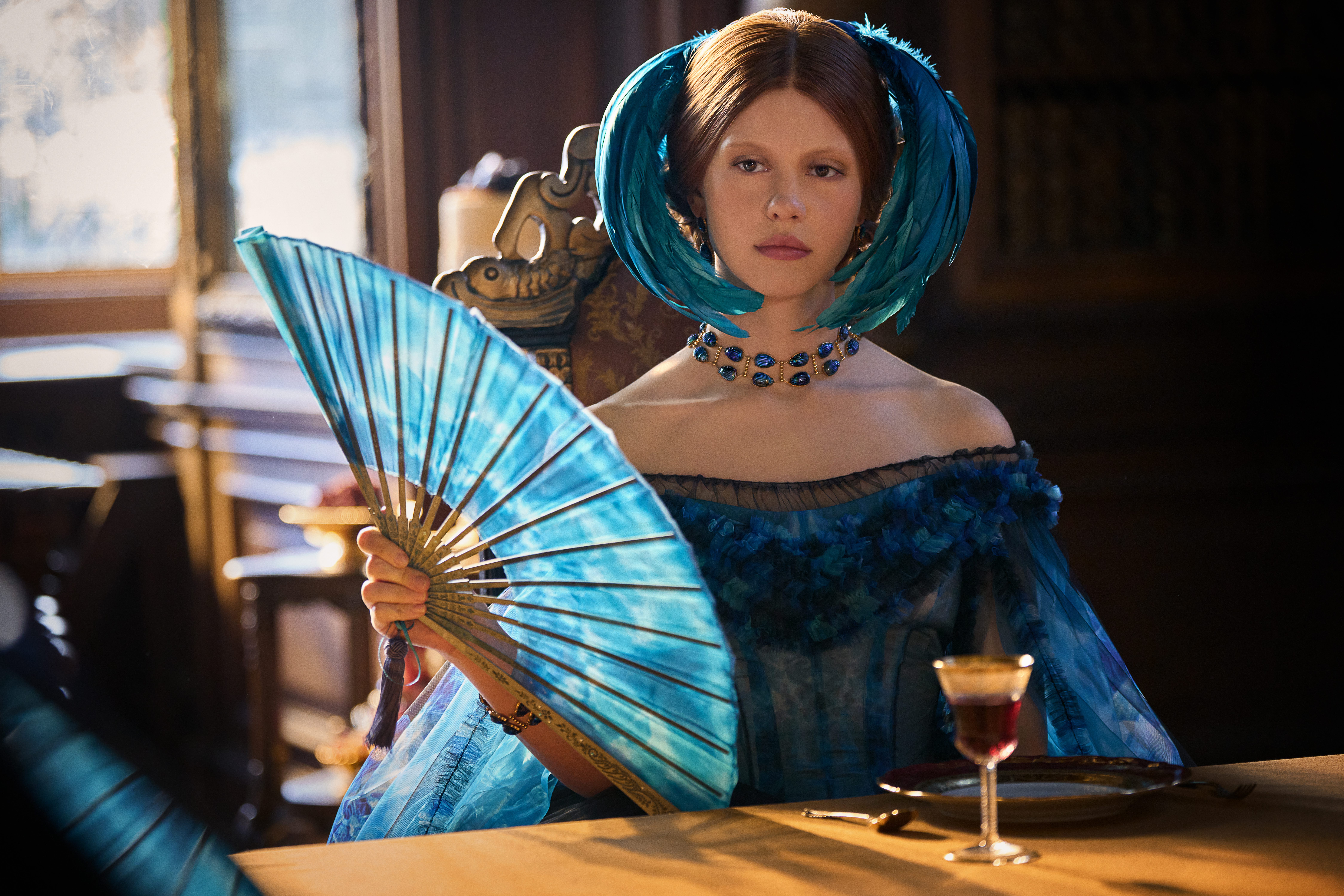 mia goth as elizabeth in a blue dress and feather headpiece in frankenstein