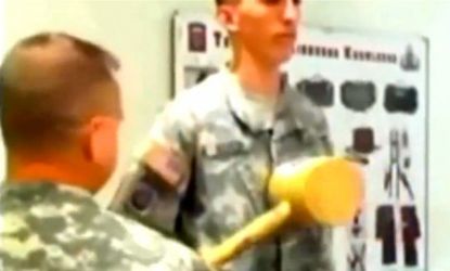 In this video screen shot, an officer warms up his swing before hitting a newly promoted sergeant in the chest with a mallet.