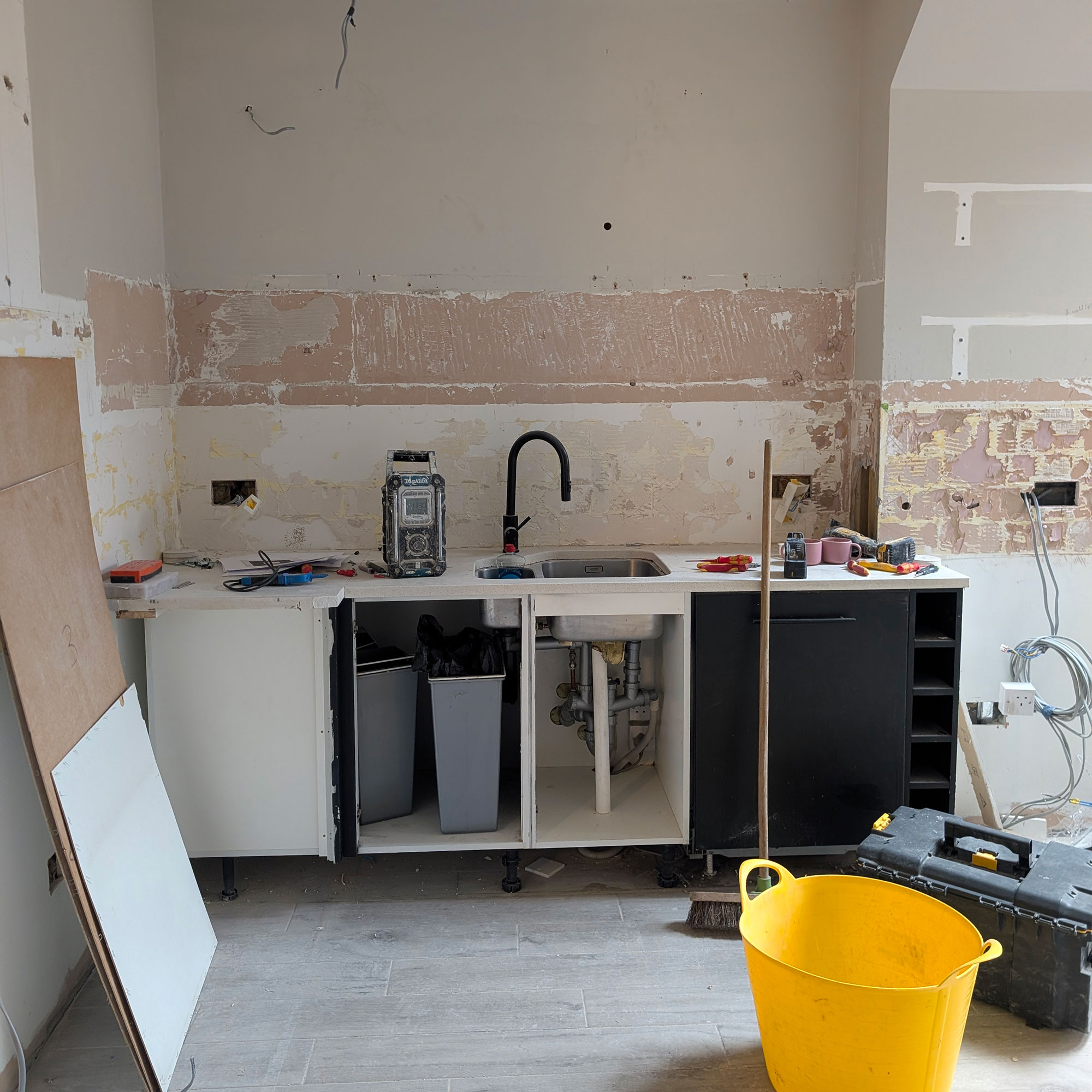 Temporary sink area with open cabinetry in kitchen mid-renovation