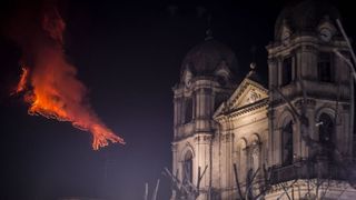 A church in Catania, Italy stands undisturbed as Mount Etna erupts miles away.