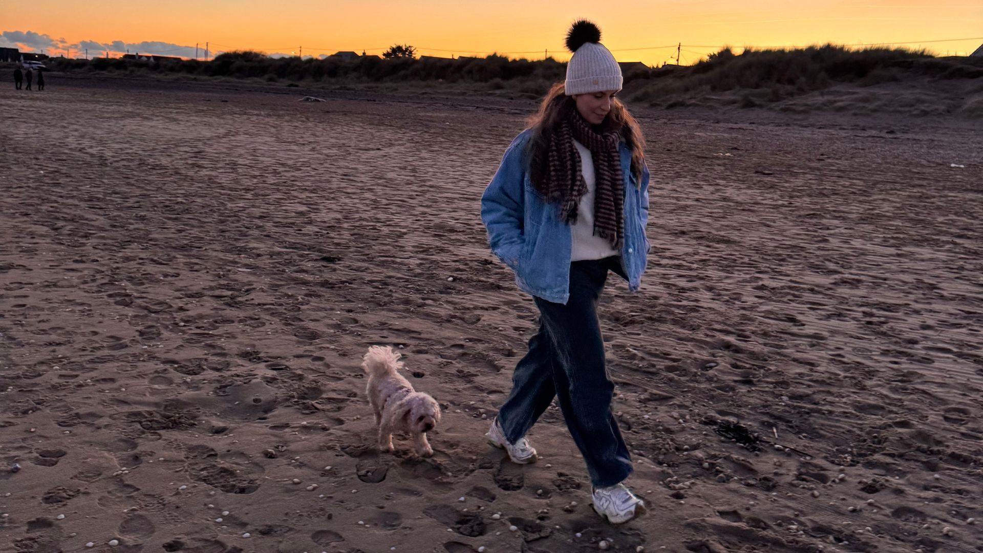 Anna Bartter walking along beach at sunset with dog