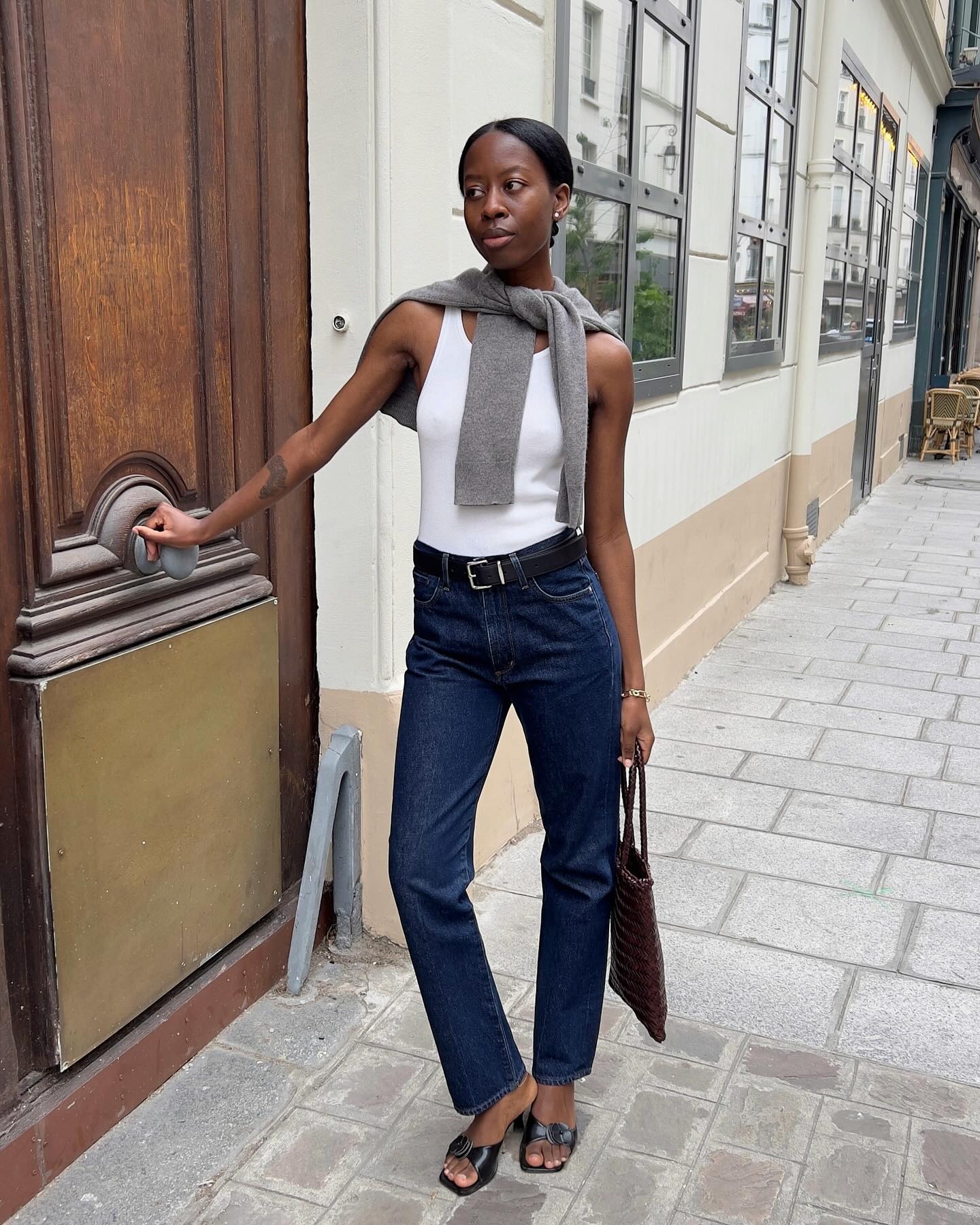 French woman wearing a sweater over her shoulders.