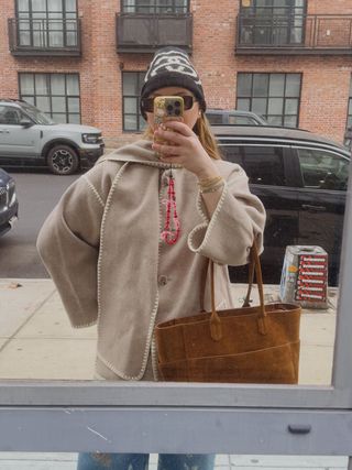 Copelyn Bengel in a Quince wool scarf coat and holding a Quince suede tote bag.