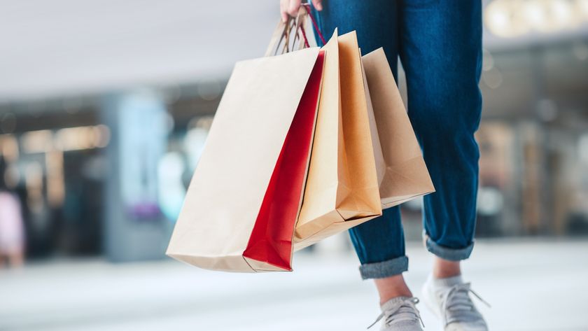 A picture of a person walking wearing jeans and sneakers from the waist down holding shopping bags