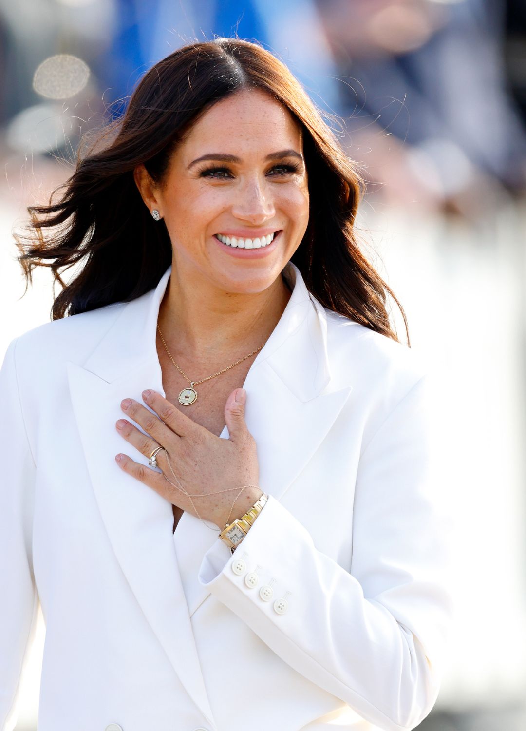 Meghan Markle in a white jacket, wearing the gold Cartier Tank watch