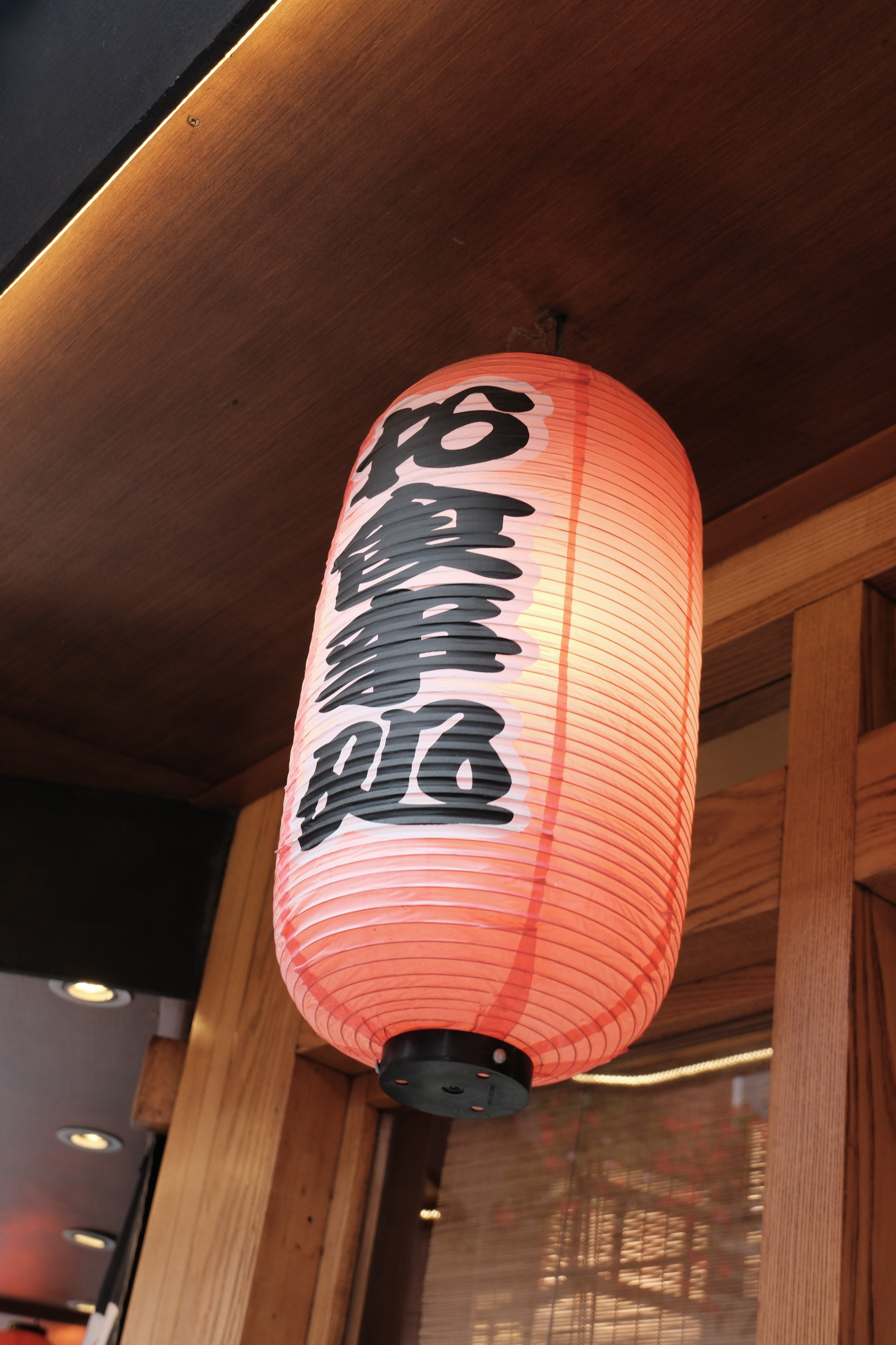 A paper lantern with Chinese writing outside of a restaurant