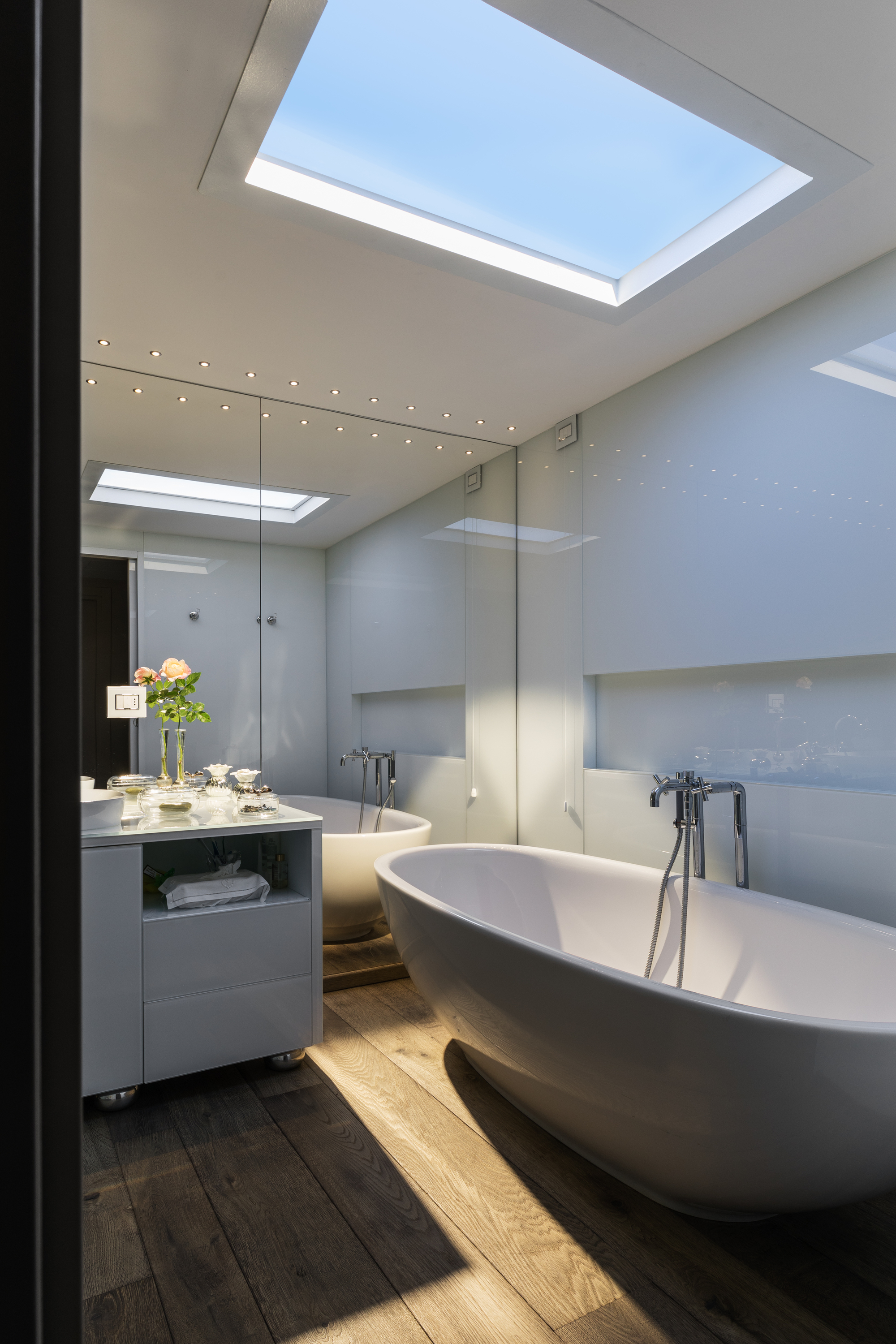 bathroom with coelux light box, wall of mirrors, freestanding bath and vanity with timber-look floor tiles