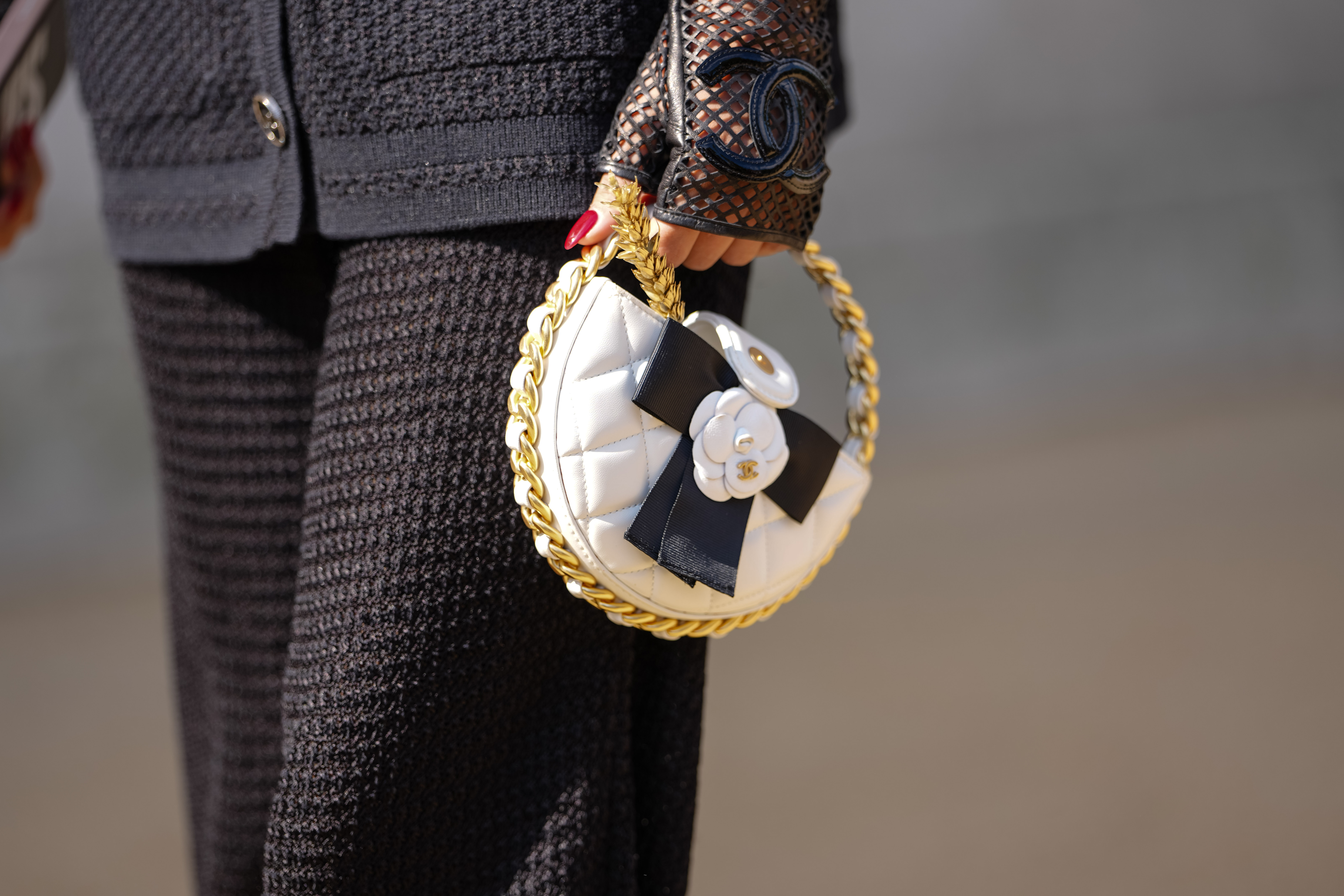 Close-up of someone dressed all in black's hand holding a Chanel bag