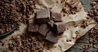 Squares of chocolate and grated up chocolate on brown paper