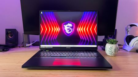 MSI Titan 18 HX gaming laptop open on desktop with a potted plant on a wooden desk