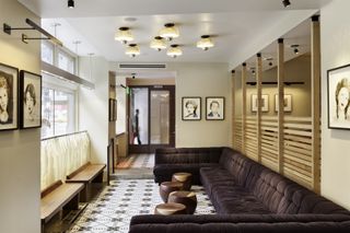 A metropole lounge in a hotel features 1970s-inspired decor in brown tones, including a huge modular sofa shaped like a reversed C.