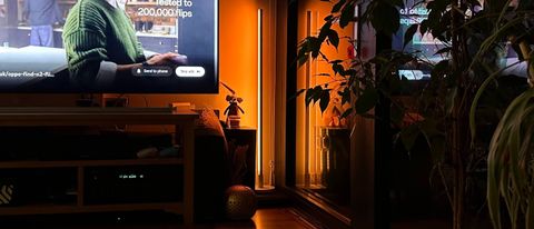 Wiz Luminaire Pole Floor Light glowing orange in a living room corner.