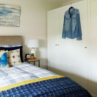 bedroom with hanging shirt on wardrobe storage and lamp