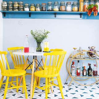 Kitchen with blue shelf, round table and yellow dining chairs