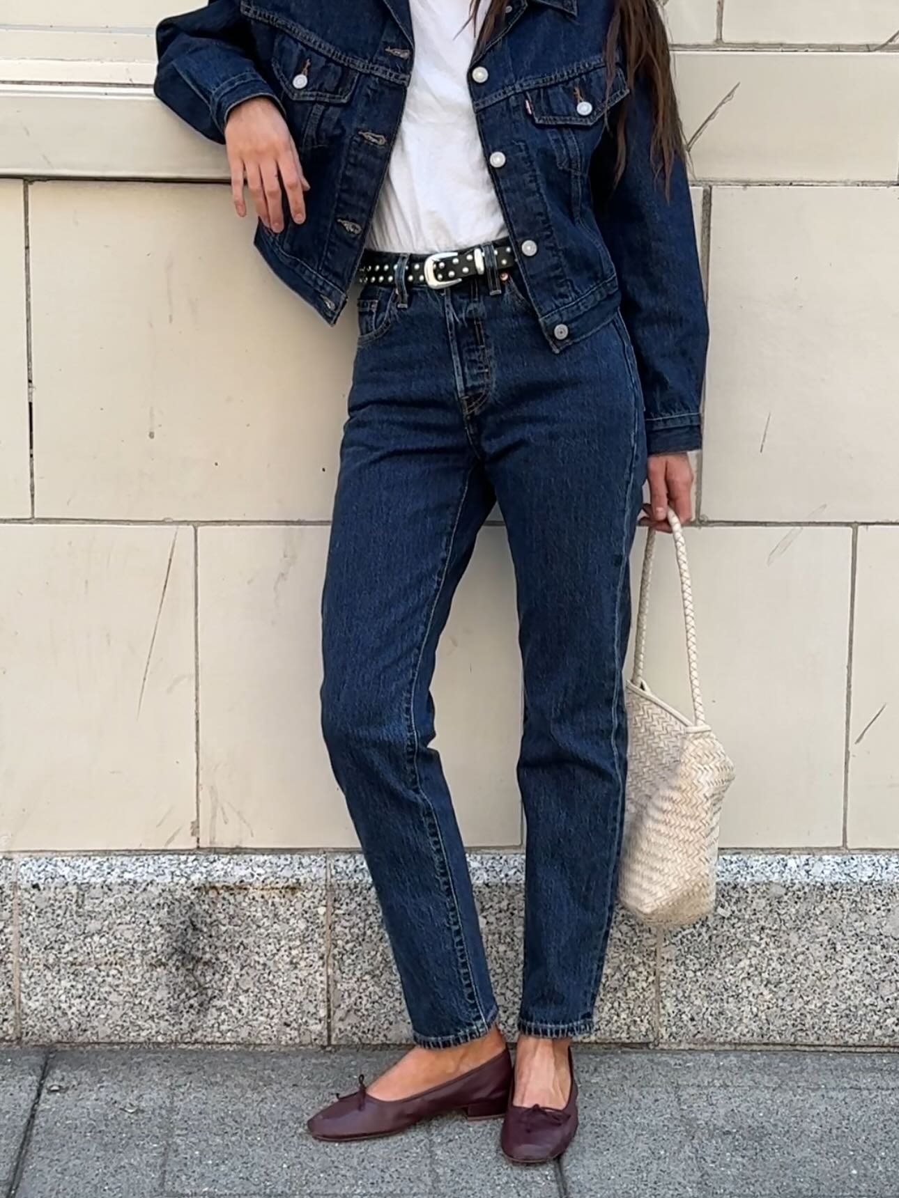 Influencer @makenna_alyse wears cigarette jeans with burgundy ballet flats, a denim jacket and a black studded belt.