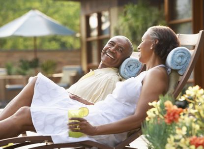 A happy retired couple lounges by a pool