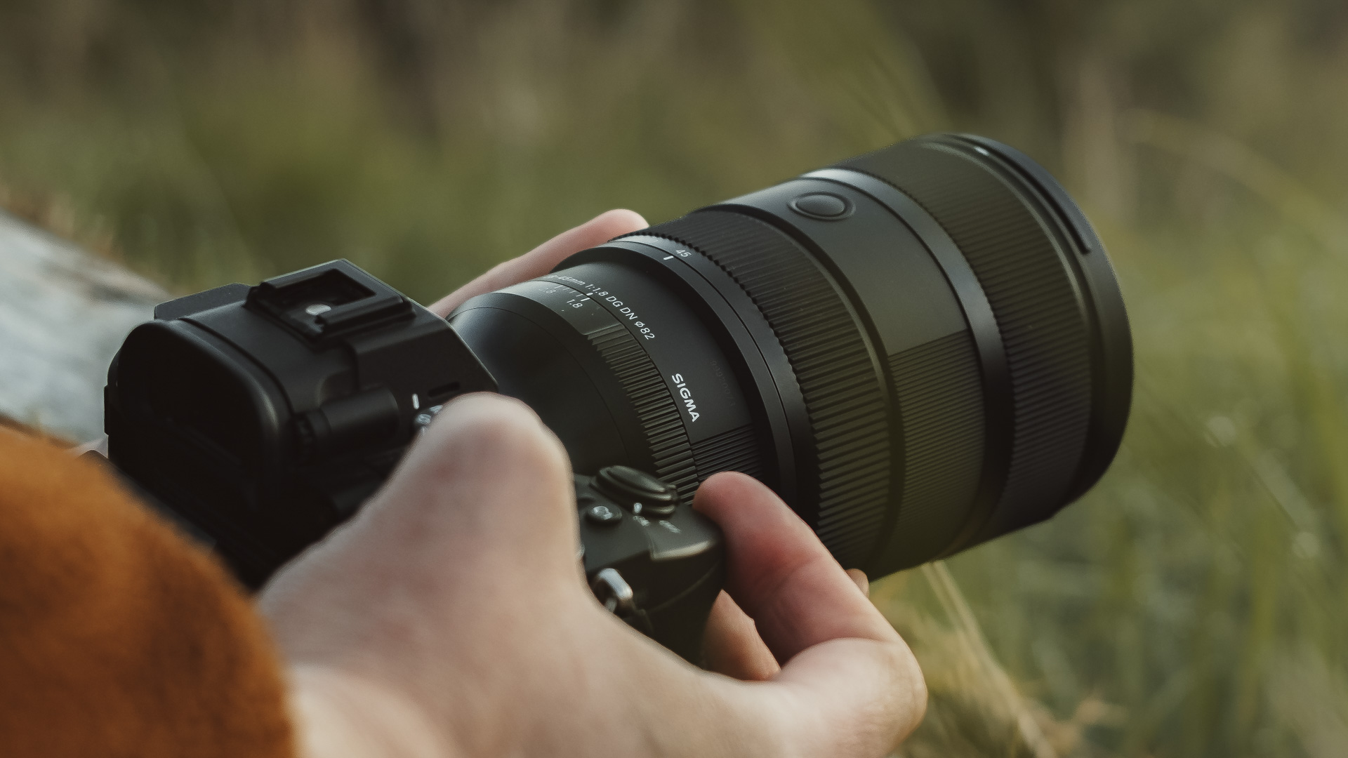 Sigma 28-45mm F1.8 lens mounted on a Sony camera being held by a photographer