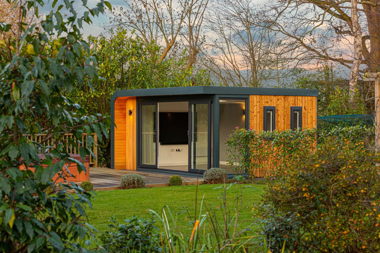 Modern garden office clad in warm wood in a large garden 