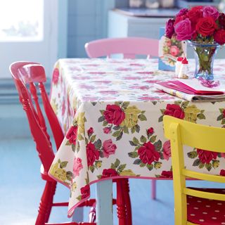 dining table with floral printed table cloth and red chair