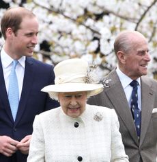 Prince William, Queen Elizabeth and Prince Philip standing in front of a flowering tree and smiling