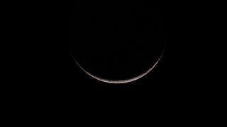 a tiny sliver of crescent moon in the night sky