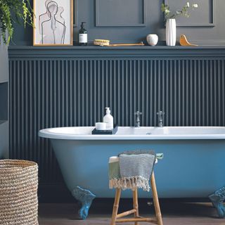 Navy bathroom with wall panelling and blue bath.