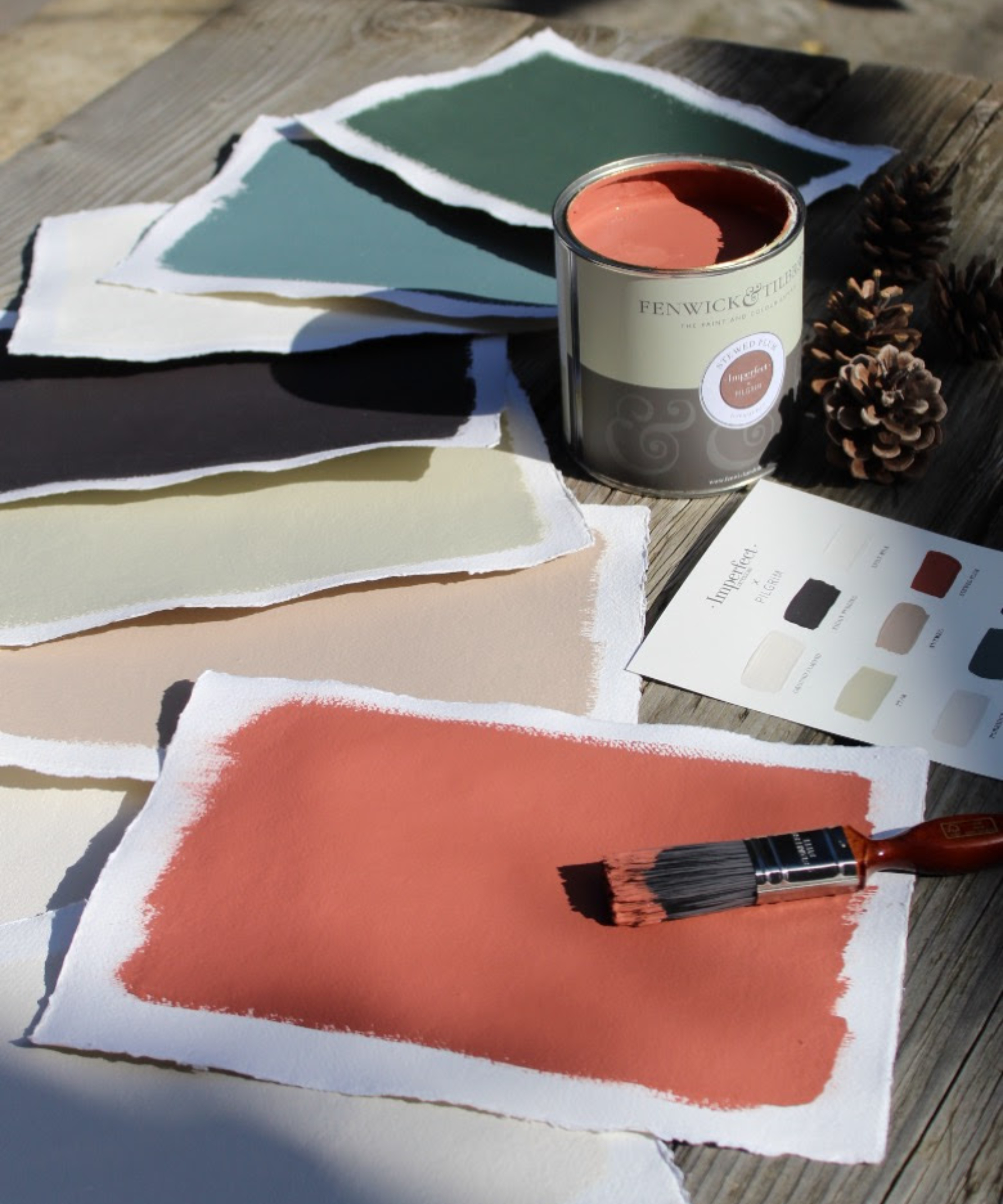 can of paint with sheets of paper painted in different shades and paint brush resting on one sheet