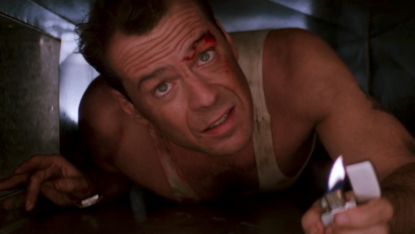 Bruce Willis as John McClane in a vent with a lit match in Die Hard