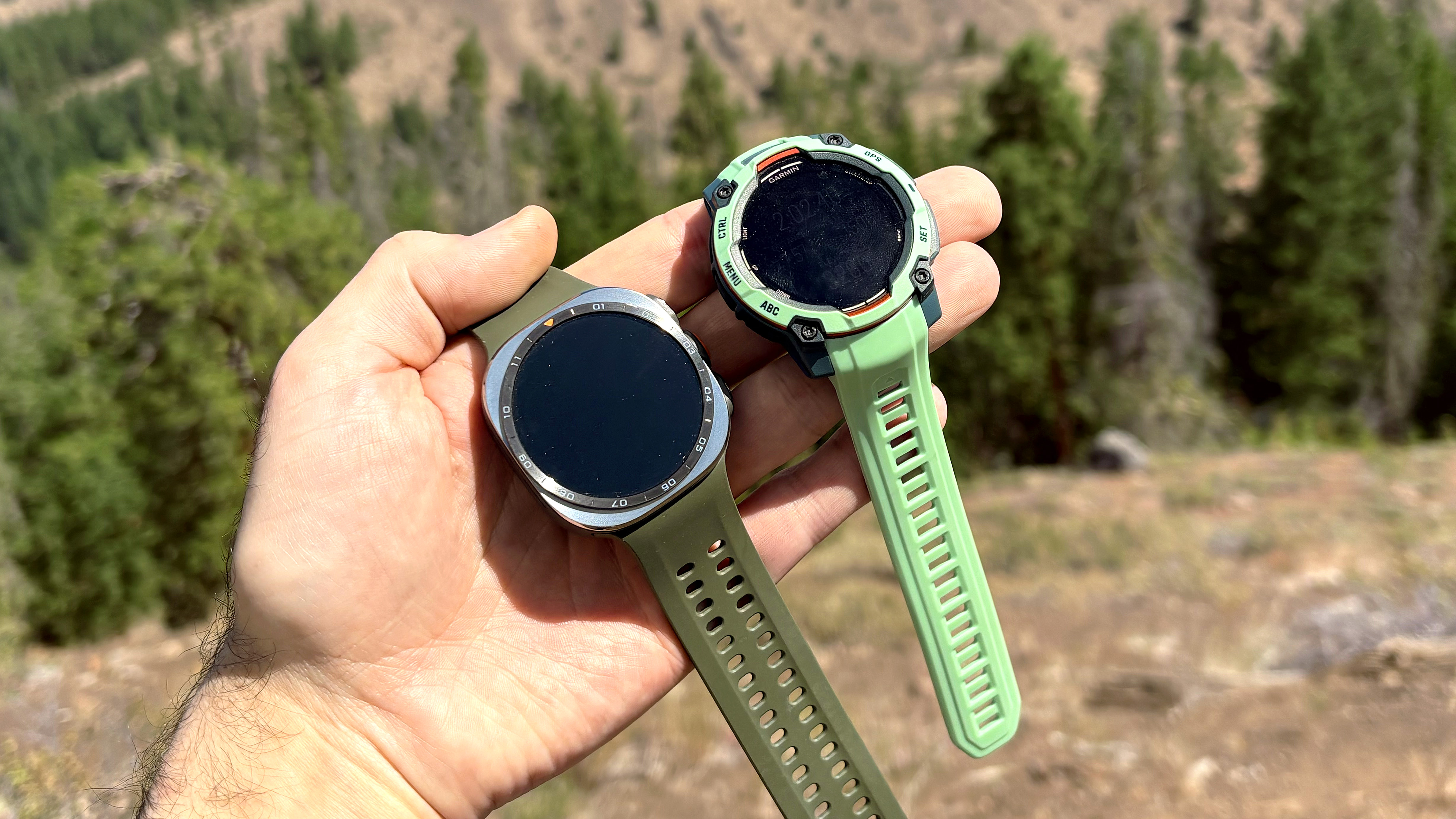 Close-up of the Samsung Galaxy Watch Ultra 2 and Garmin Instinct 3 in the mountains during an e-biking excursion