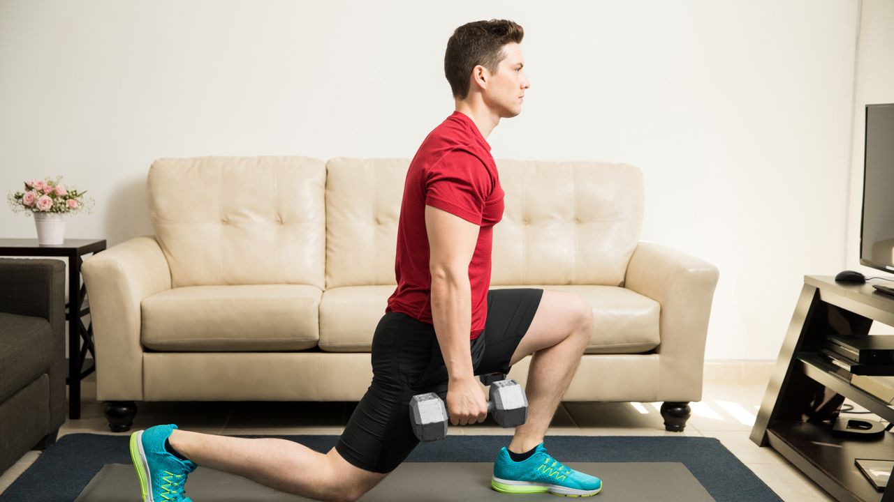 A man performing a dumbbell strength training workout at home