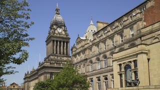 A wide angle shot of architecture in Leeds, with a large and intricate dome and clocktower