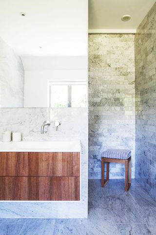 modern bathroom with marble tiled walls and floors and wooden wall-hung storage