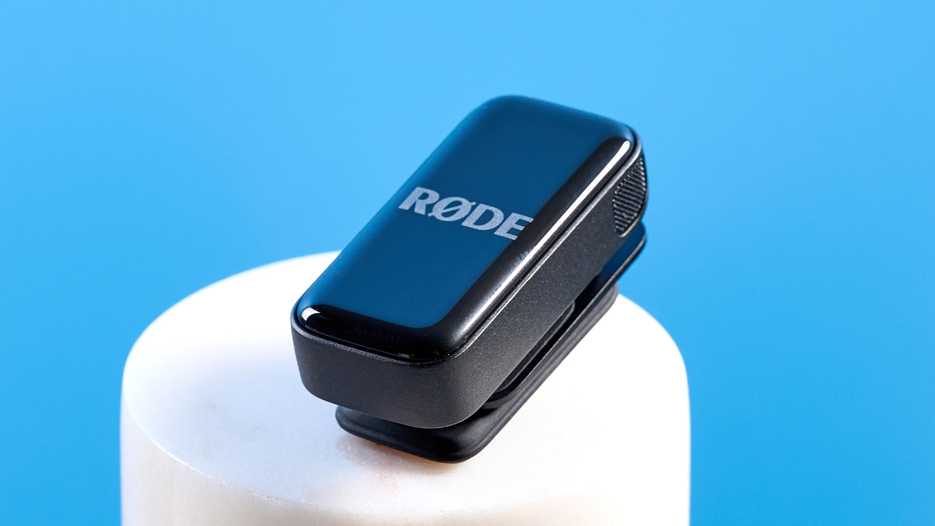 the rode wireless micro microphone with the black charging case and two black transmitter mics photographed against a blue background