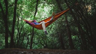 Man relaxing in hammock in forest