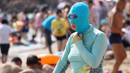 A Chinese beachgoer wearing a bathing suit and head mask 