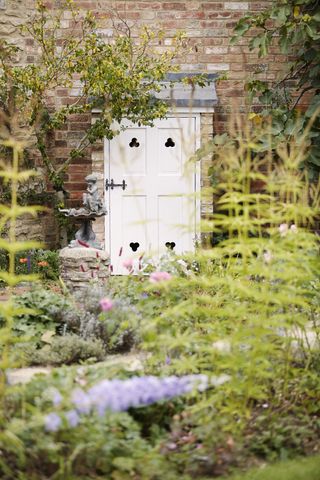 white door in garden by stone cherub statue