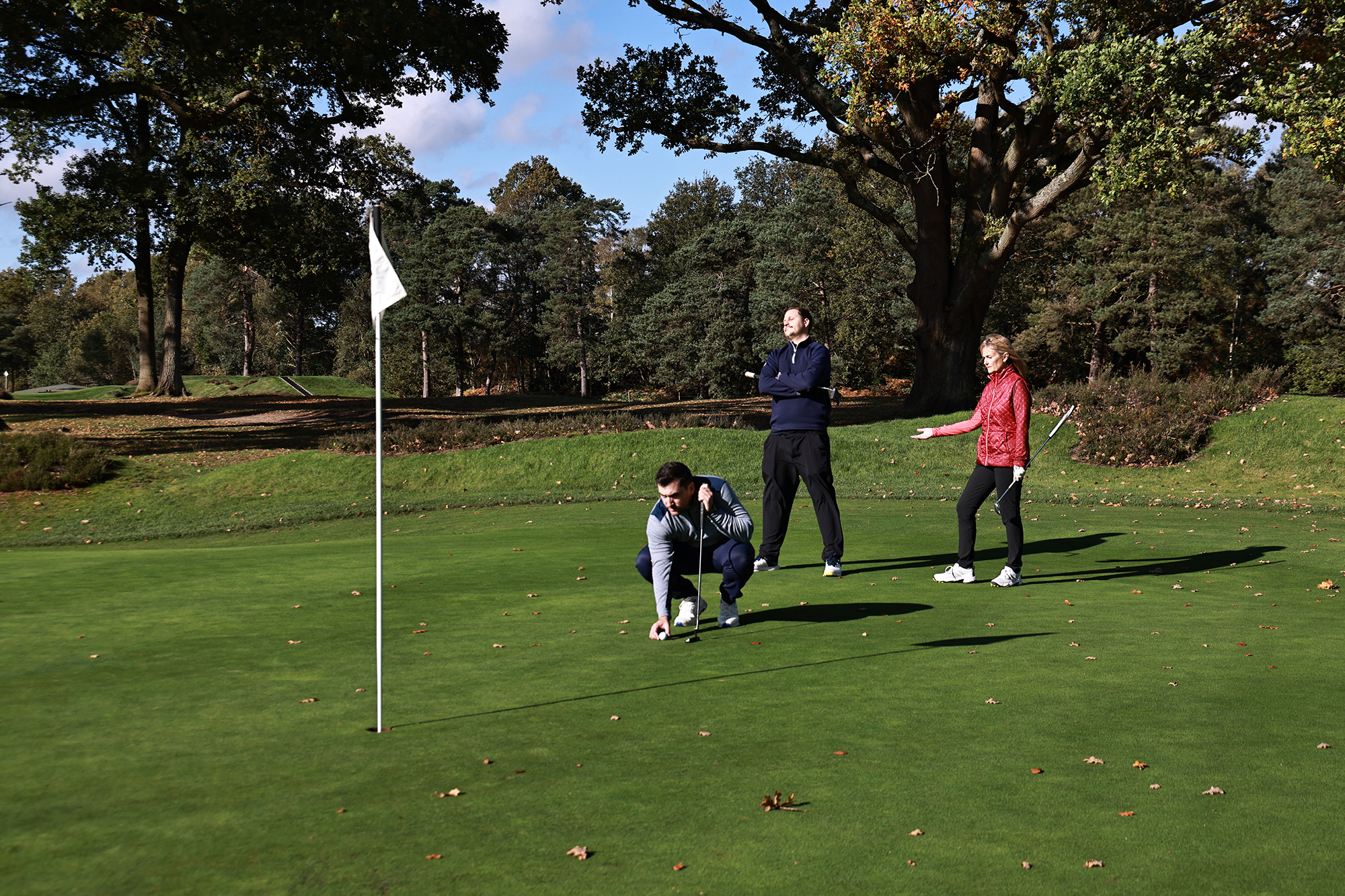 Sam De'Ath, Alison Root and Nick Bonfield on the green of the golf course, with Alison and Nick becoming frustrated with Sam's slow play