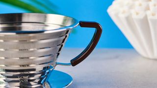 kalita wave stainless steel pour-over coffee dripper photographed against a blue background with kalita filters