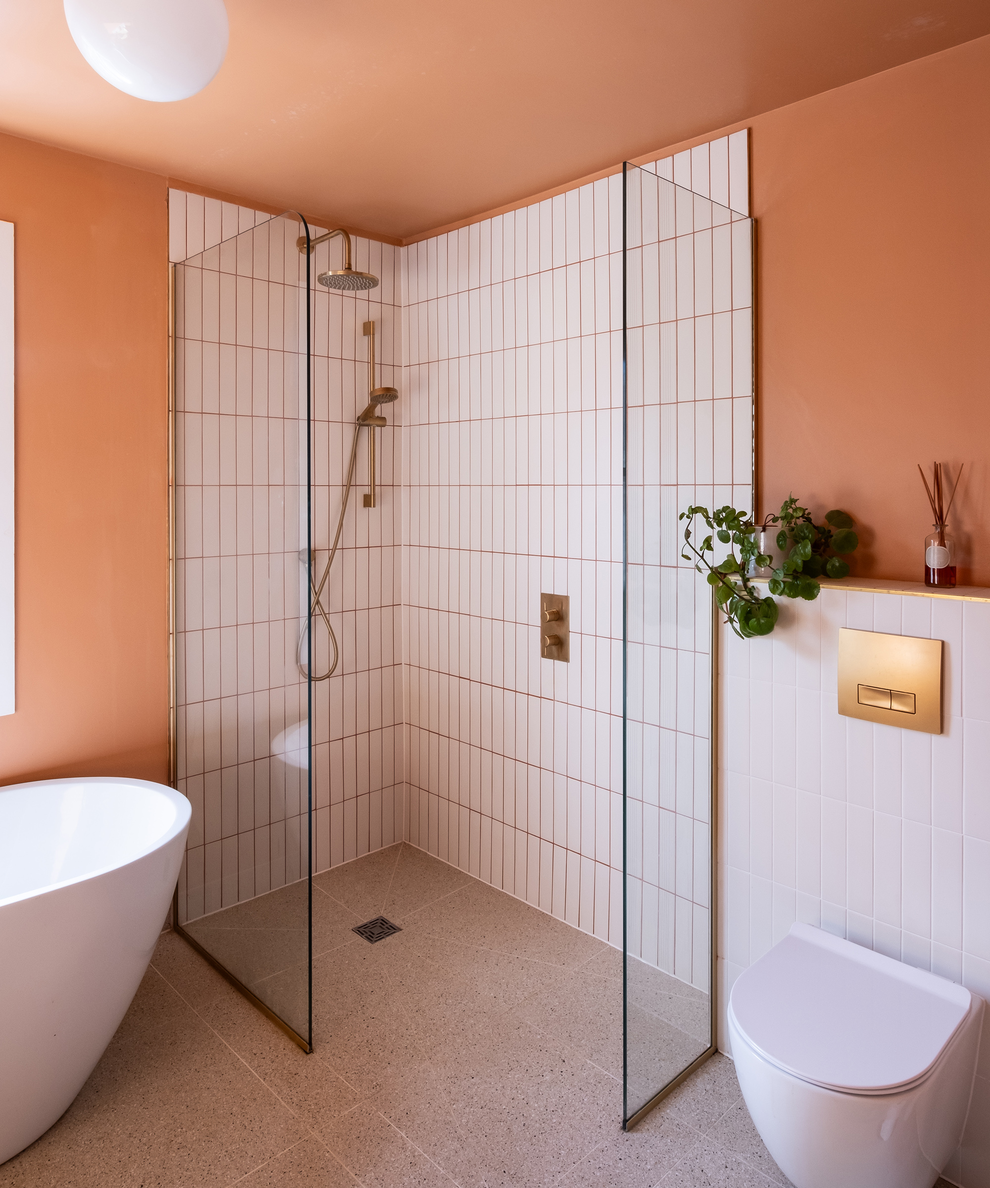 A shower enclosure with white tiles and a contrasting grout. The shower fixtures are brass in colour