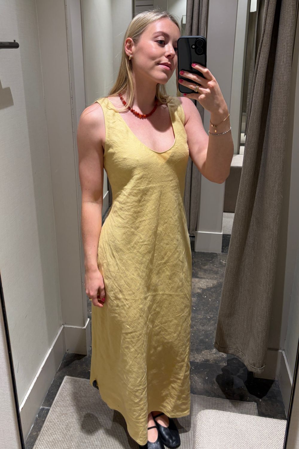 Woman wears yellow linen dress and black ballet flats