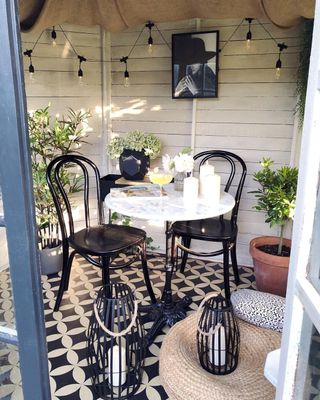 Inside of a she shed with patterned lino flooring, a table and two chairs