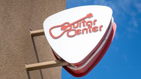 Close-up of pick-shaped logo sign at Guitar Center store in Emeryville, California with logo visible, November 12, 2025