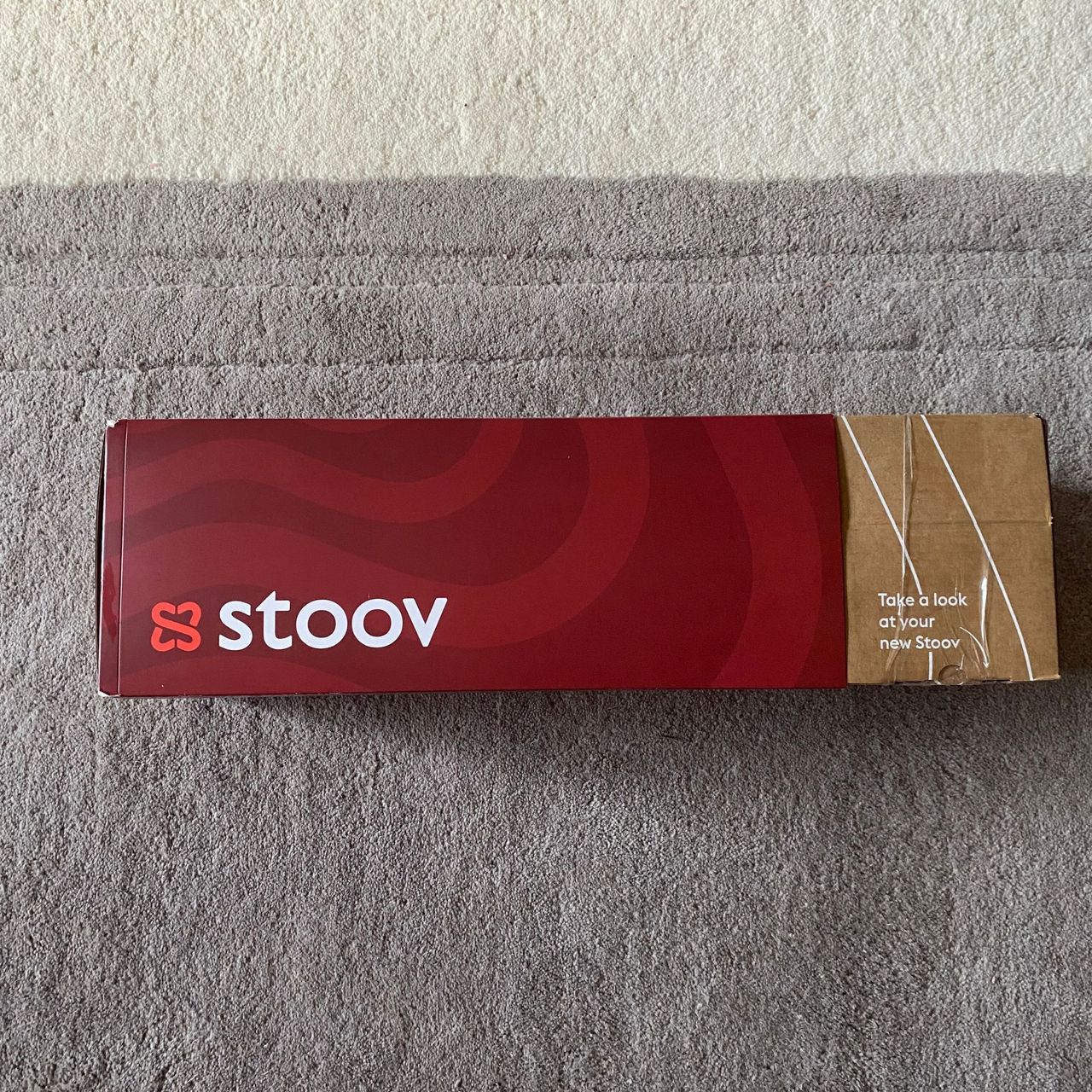 The box of the Stoov Big Hug3 on a grey rug