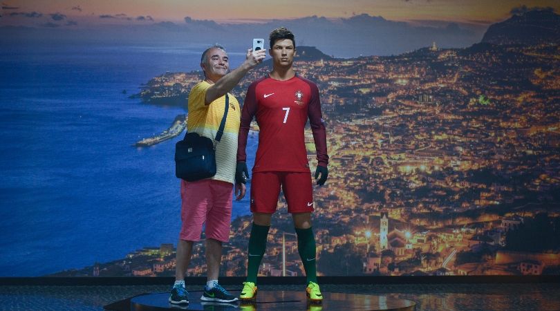 A man poses next to a waxwork of Cristiano Ronaldo at the forward&#039;s museum in Madeira in 2018.