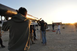 side shot of students holding a rocket in the desert as the sun rises
