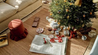 Rowen & Wren&rsquo;s autumn/winter collection styled with a rust velvet stool, natural jute rug, softly wrapped gifts and a traditional Christmas tree.