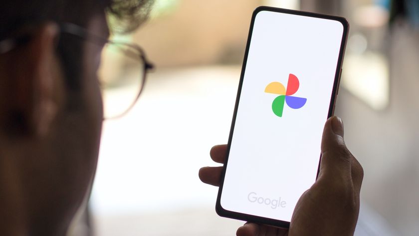 A man staring at a phone with the Google Photos logo on it