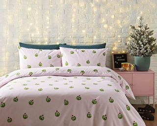 A bedroom with pink duvet with sprout motif and mini tree