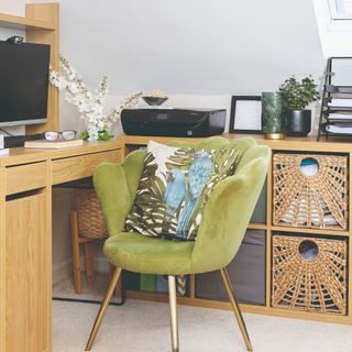 A home office with a corner desk and storage set up and a green velvet chair